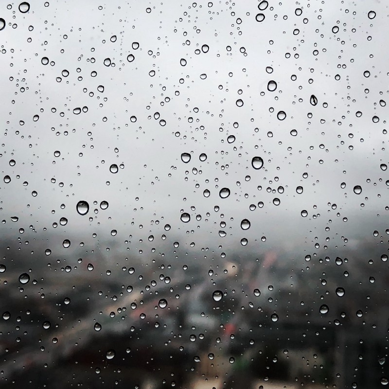 Rain drops in focus, with a Lo-Fi shot of the city in the background.